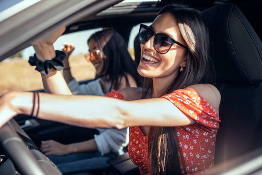 Two friends sing along to a song while driving.